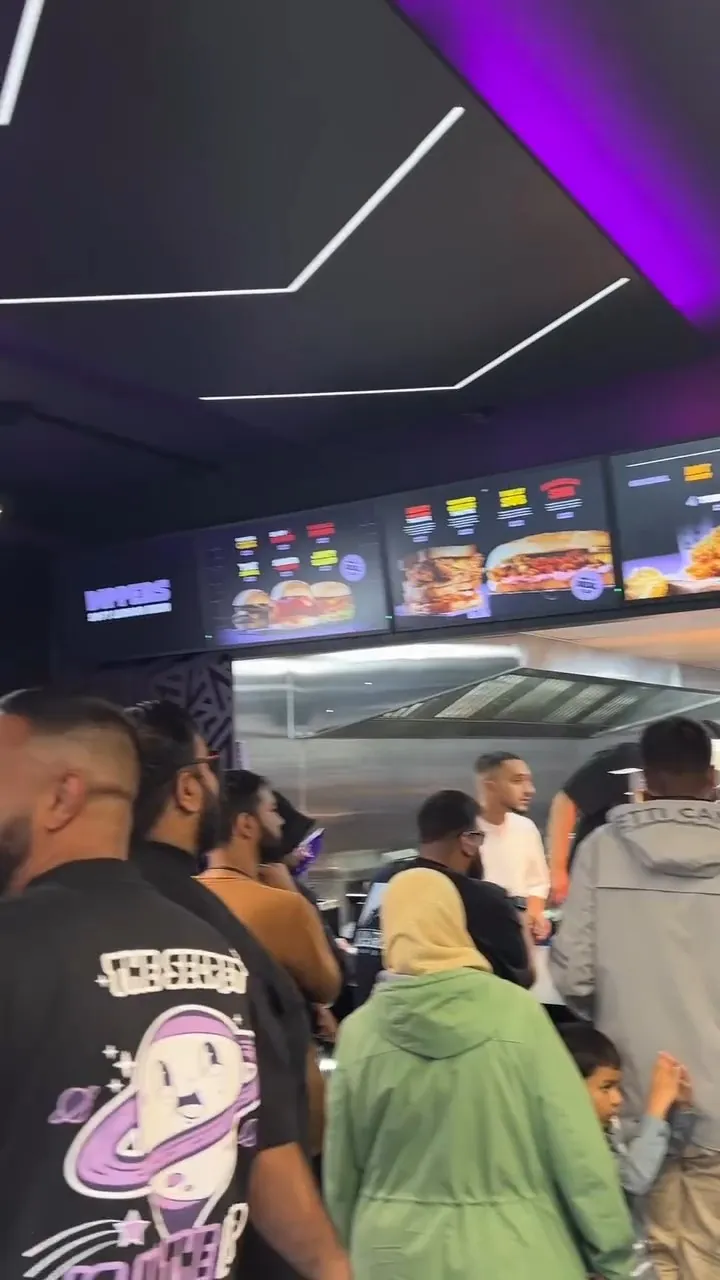 Queue at the Dippers counter under purple neon